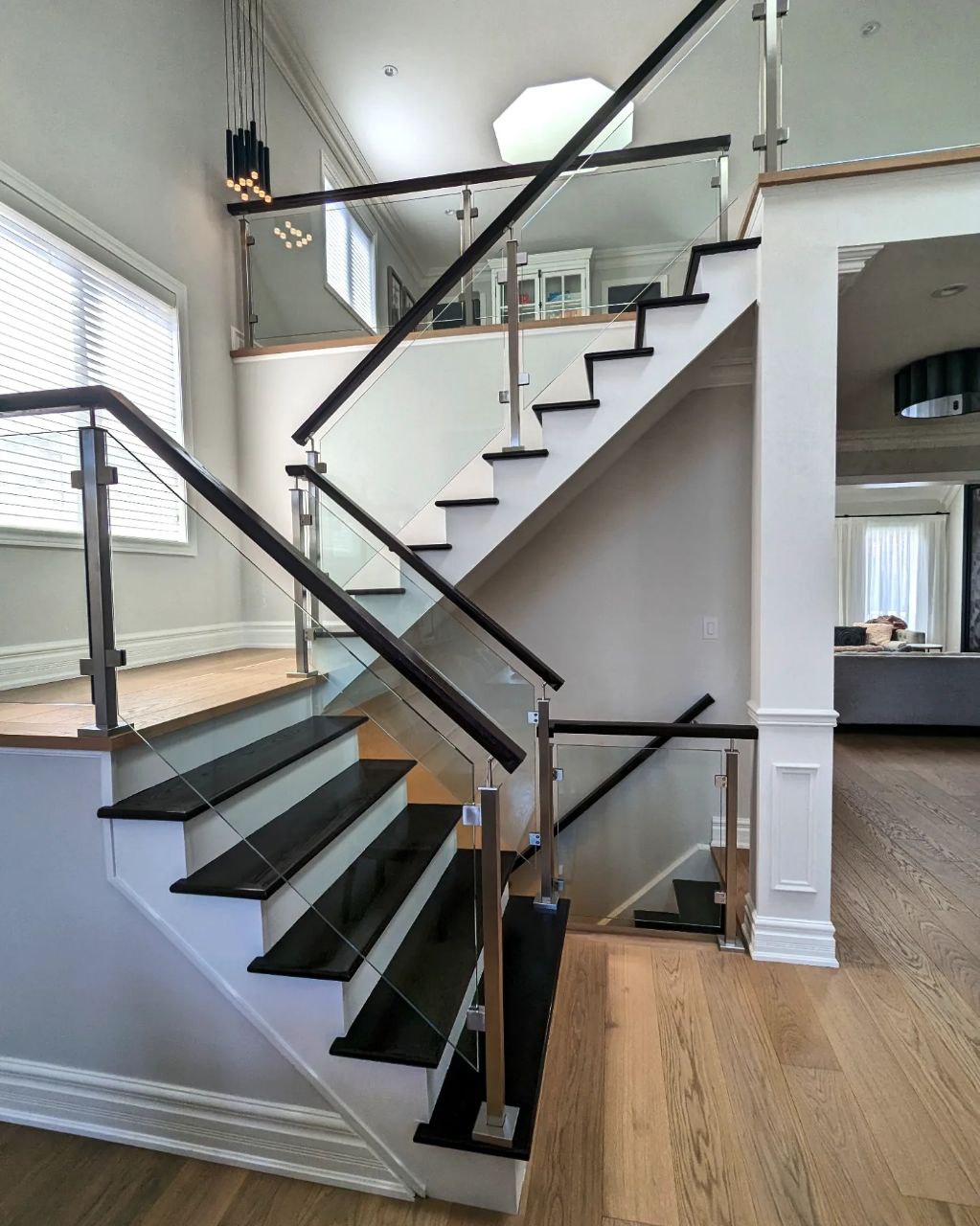 Stairs refinishing project in Oakville during a full renovation of a house. Varnished treads, painted white risers, stained handrail installed. The wall stringers and risers are painted in pure white by Sherwin Williams.