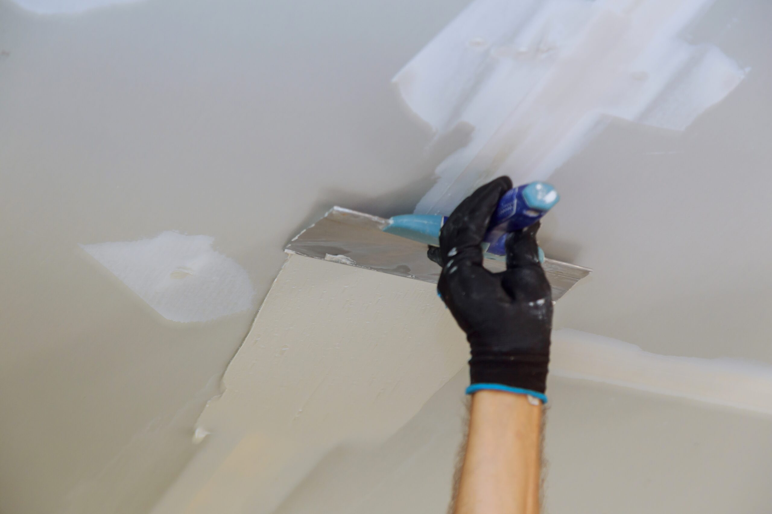 Remove loose or peeling paint from the ceiling through scraping, followed by meticulous sanding. A new layer of plaster applied to the ceilings to prepare for a new coat of paint application in a Deer Park home.