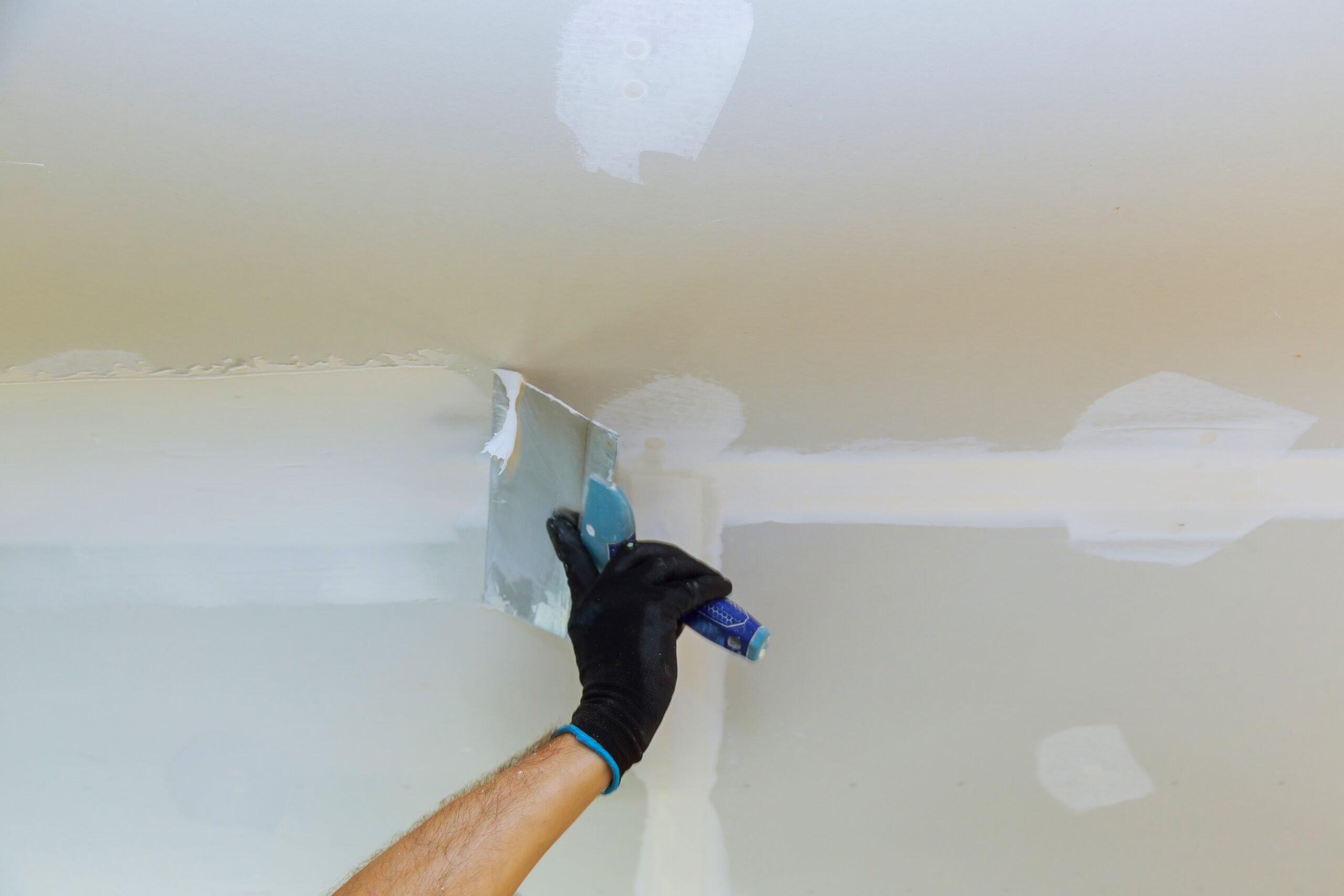 Remove loose or peeling paint from the ceiling through scraping, followed by meticulous sanding. A new layer of plaster applied to the ceilings to prepare for a new coat of paint application in a Deer Park home.