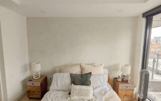 Modern Boho inspired bedroom with limewash accent wall in grayish beige color, showcasing textured finish. Limewash paint in bedroom.
