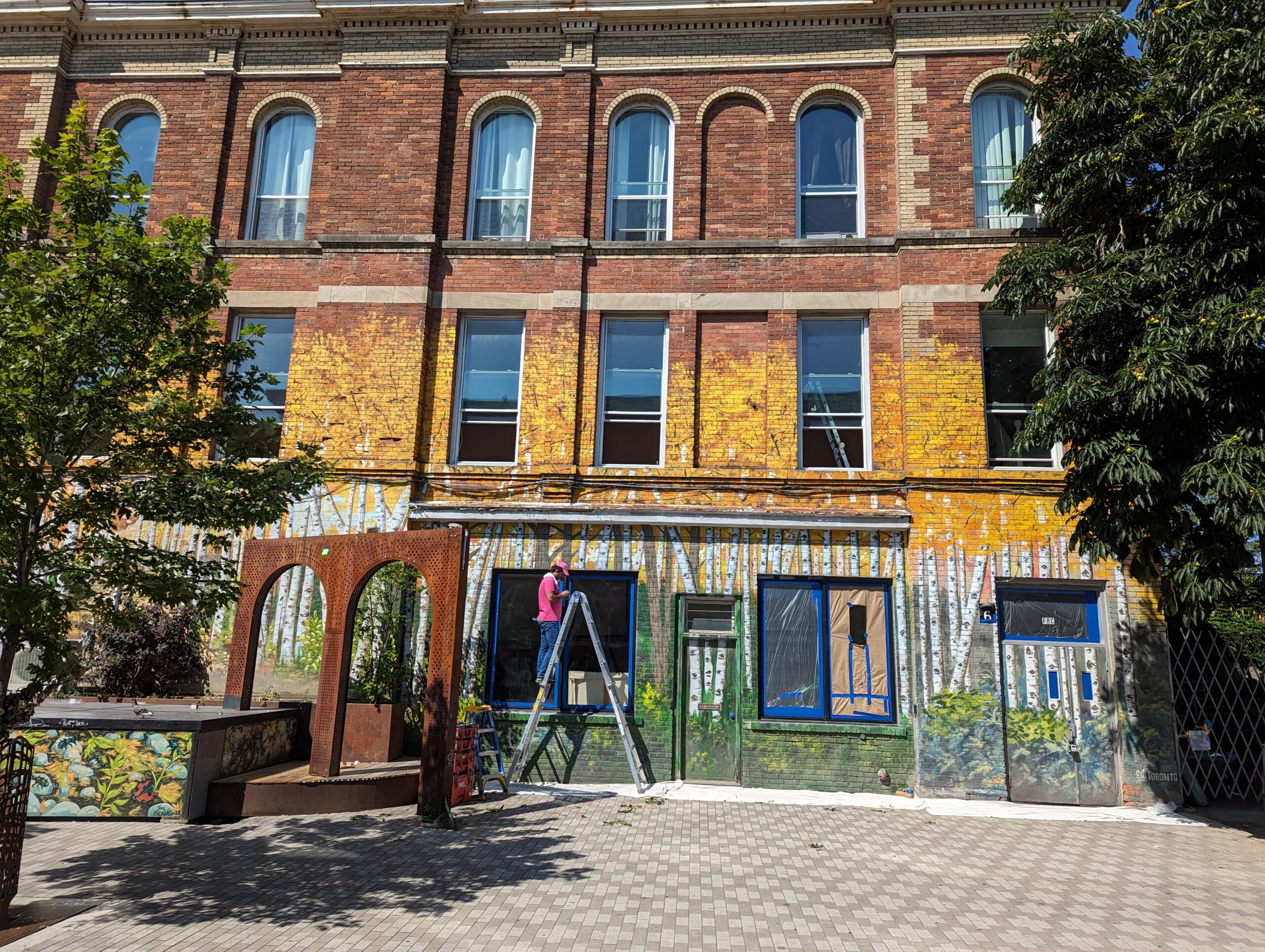 Before brick painting photo of a cafe exterior in downtown Toronto, located at the intersection of Queen Street and Bathurst. The image shows the original brick facade.