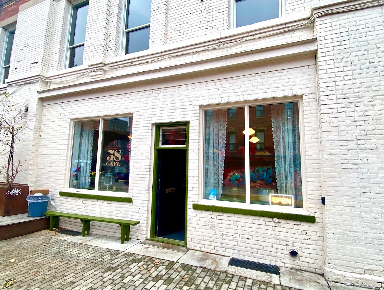 After photo of a cafe exterior in downtown Toronto, located at the intersection of Queen Street and Bathurst. The brick sprayed with white paint.