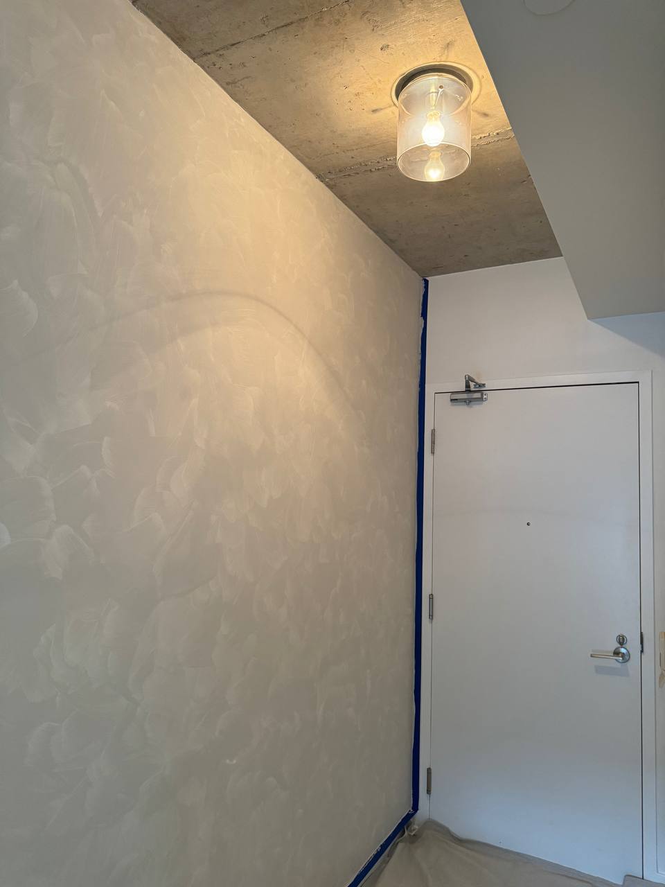 After limewash applied to an accent wall in a condo foyer, downtown Toronto, the transformation with a soft, textured finish.