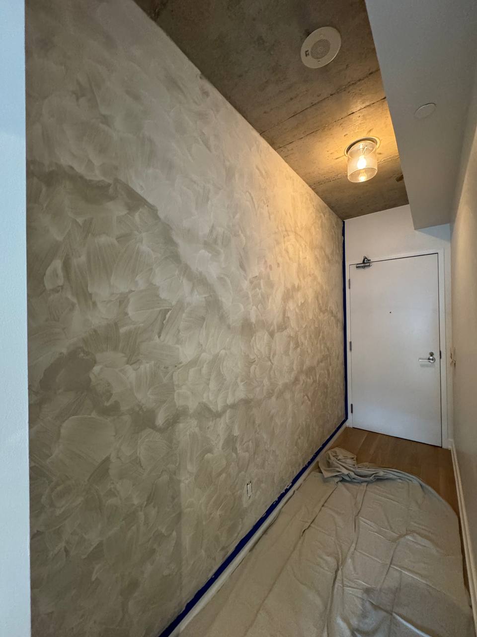 First coat of limewash applied to an accent wall in a condo foyer, downtown Toronto, beginning the transformation with a soft, textured finish.
