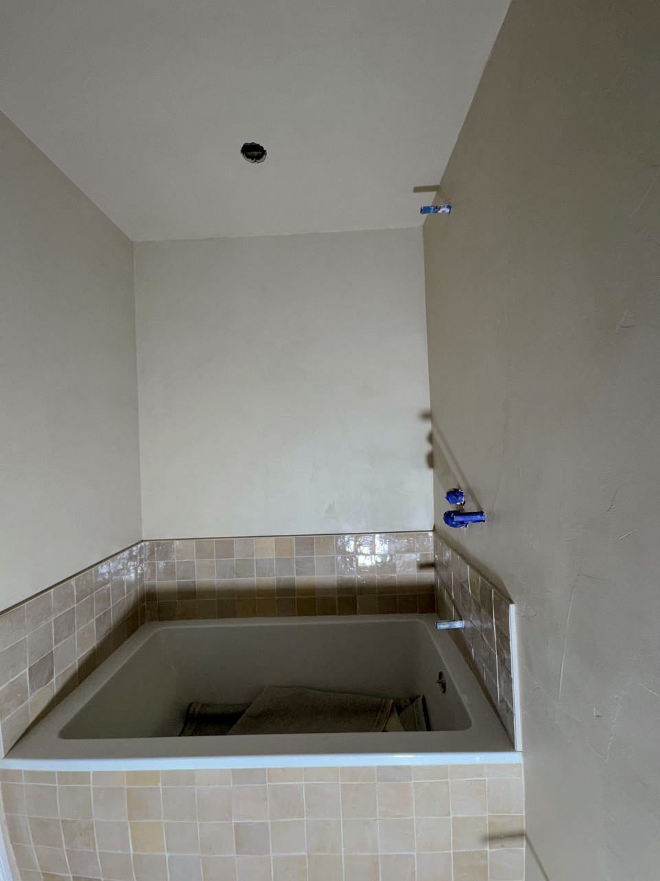 microcement-bathroom-installation-walls-ceilings-niches-in-toronto4 A contemporary bathroom with a microcement finish on the walls and ceiling, including a seamless, built-in bathtub surround. The color is a light, natural tone.