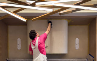 Large kitchen range hood and wall finished in a beige microcement with a matte sealant for a custom, stain-resistant surface.
