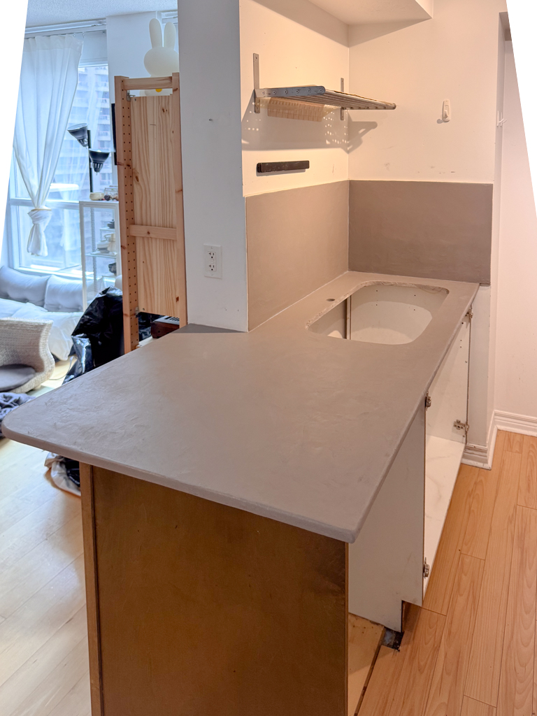 Installation of microcement over kitchen tiled backsplash and countertop in yorkville apartment, Toronto