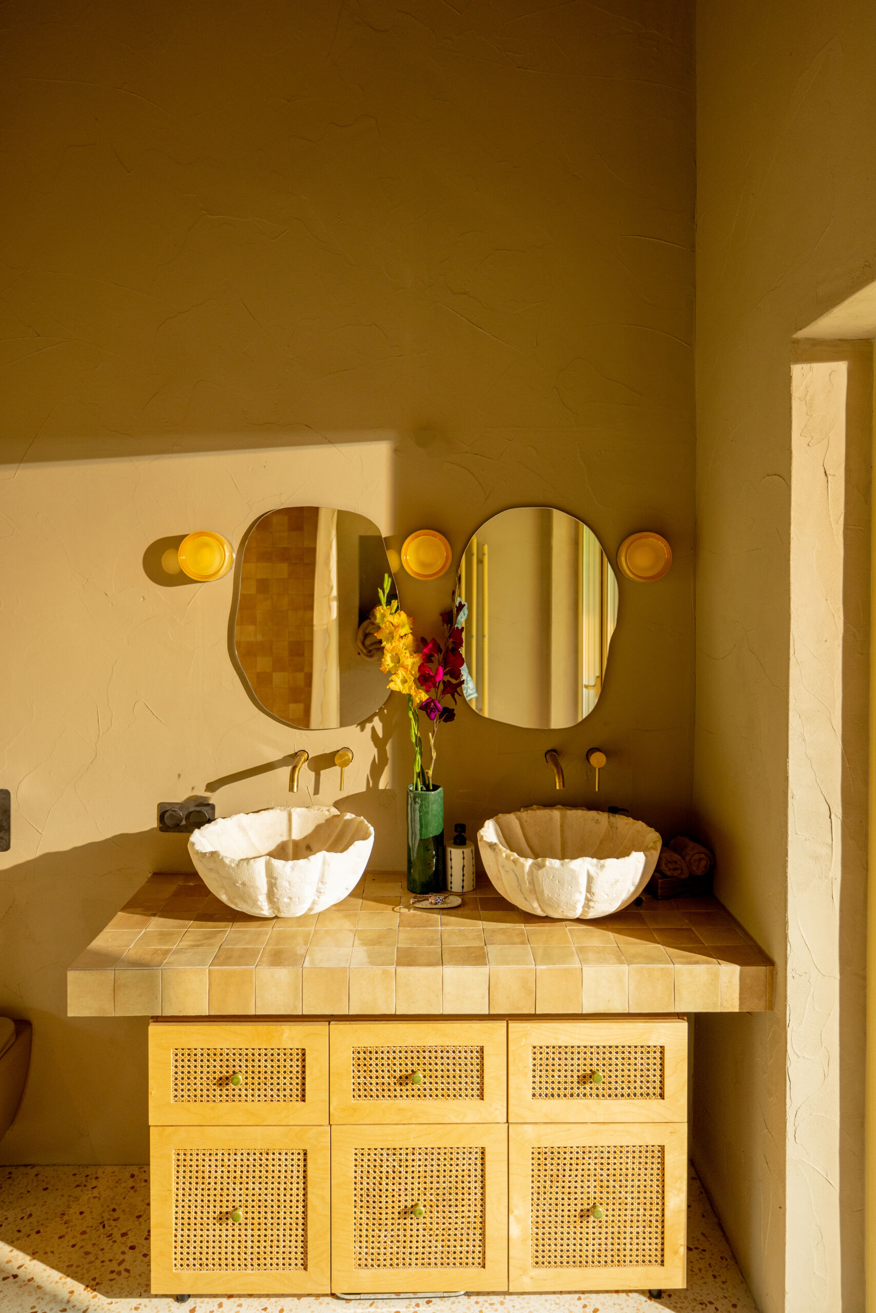 Sunlit Double Vanity with Floral Accent Close-up of customized microcement for bathroom walls, showing unique texture and trowel marks for an artisanal finish.