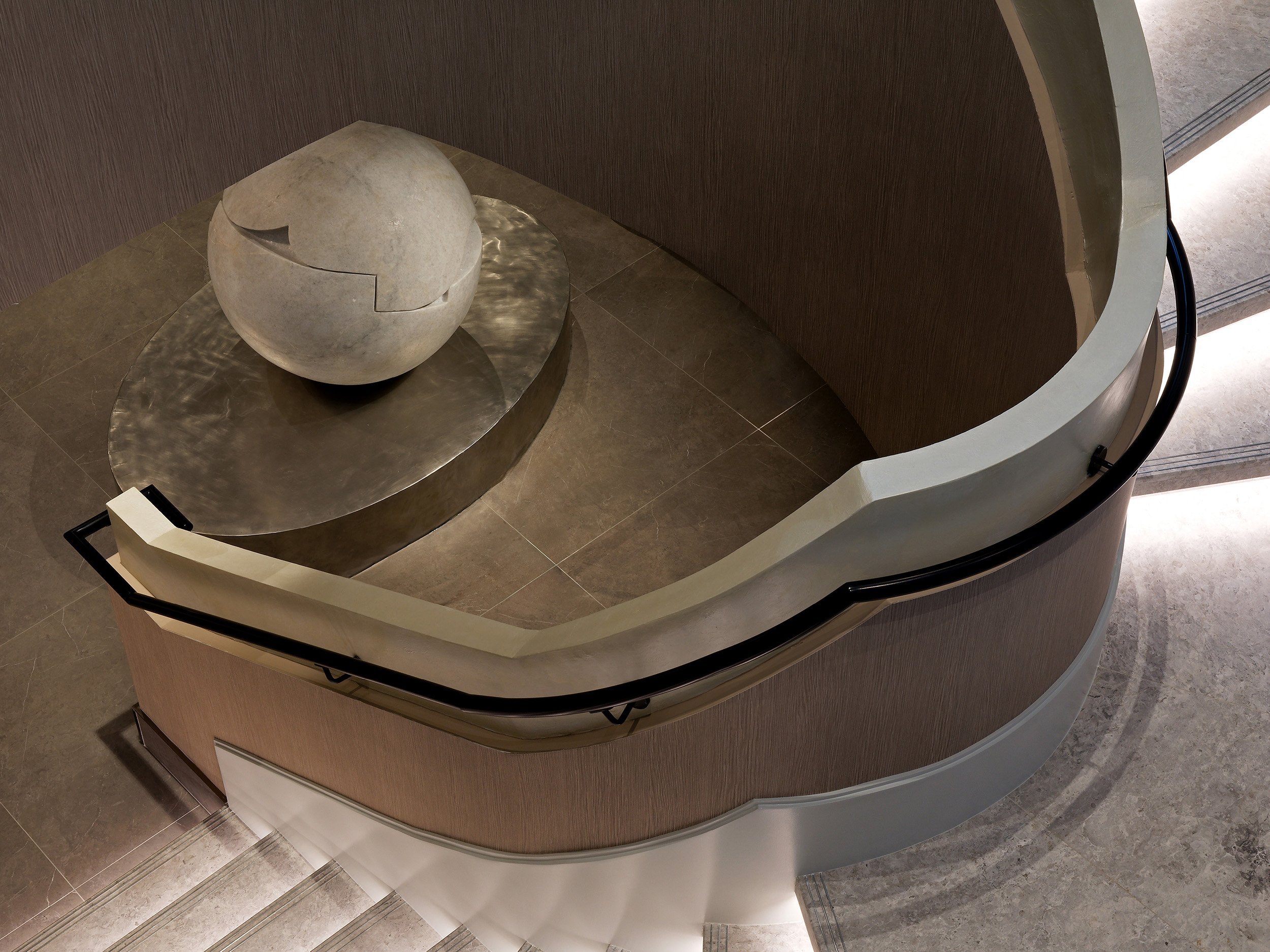 Royal-Bayview-Venetian-Plaster-Pearlescent-Handrail Close-up of a commercial lobby staircase handrail coated in smooth, shimmering pearlescent Venetian plaster.