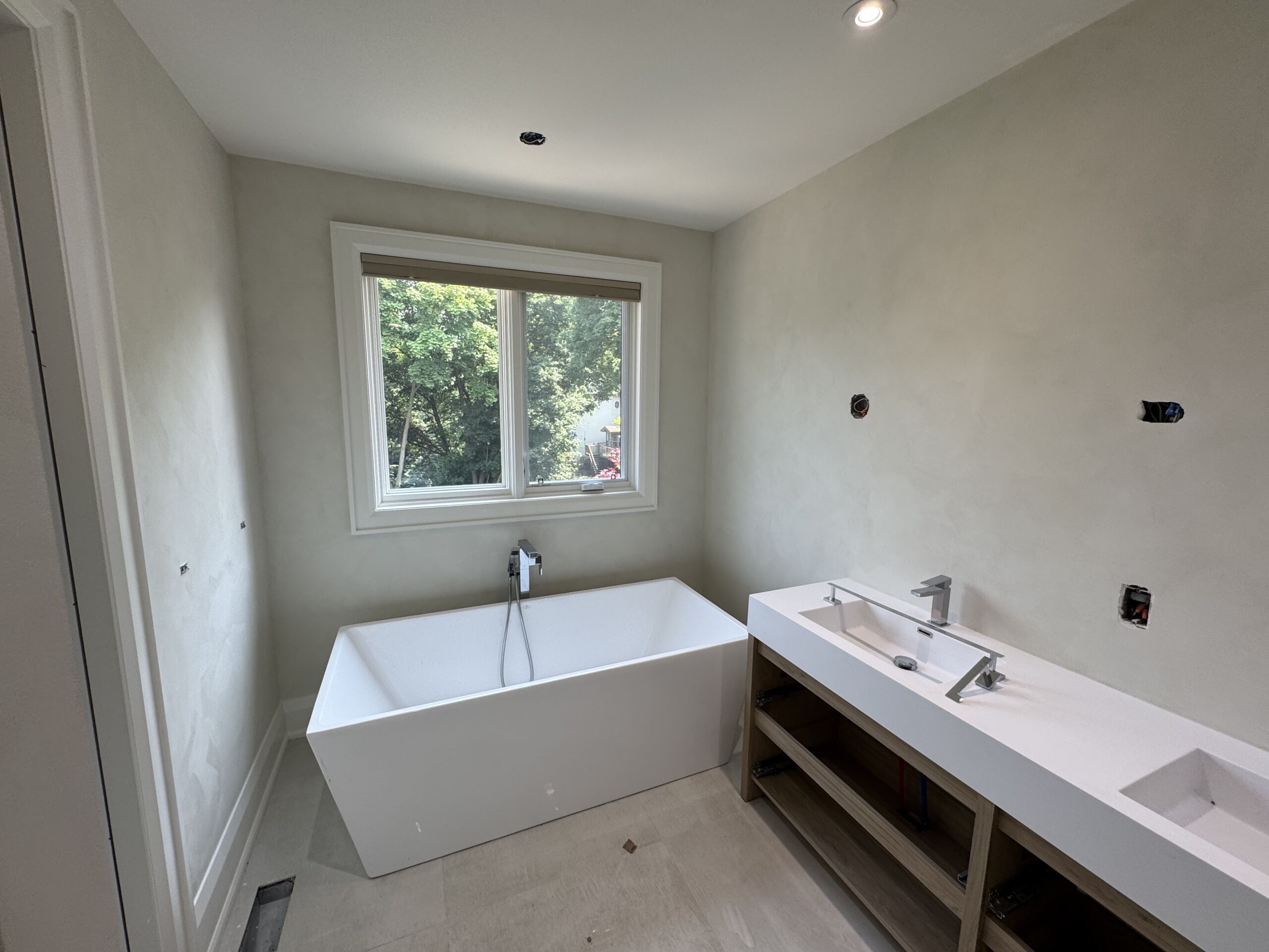 bathroom-limewash-soft-green-limewash-paint-in-toronto2 Limewash bathroom walls with freestanding tub and vanity, window framing green trees outside