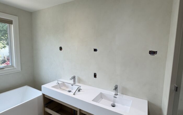 Smooth Mineral Limewash Texture: limewash bathroom walls with freestanding tub and vanity, window framing green trees outside.