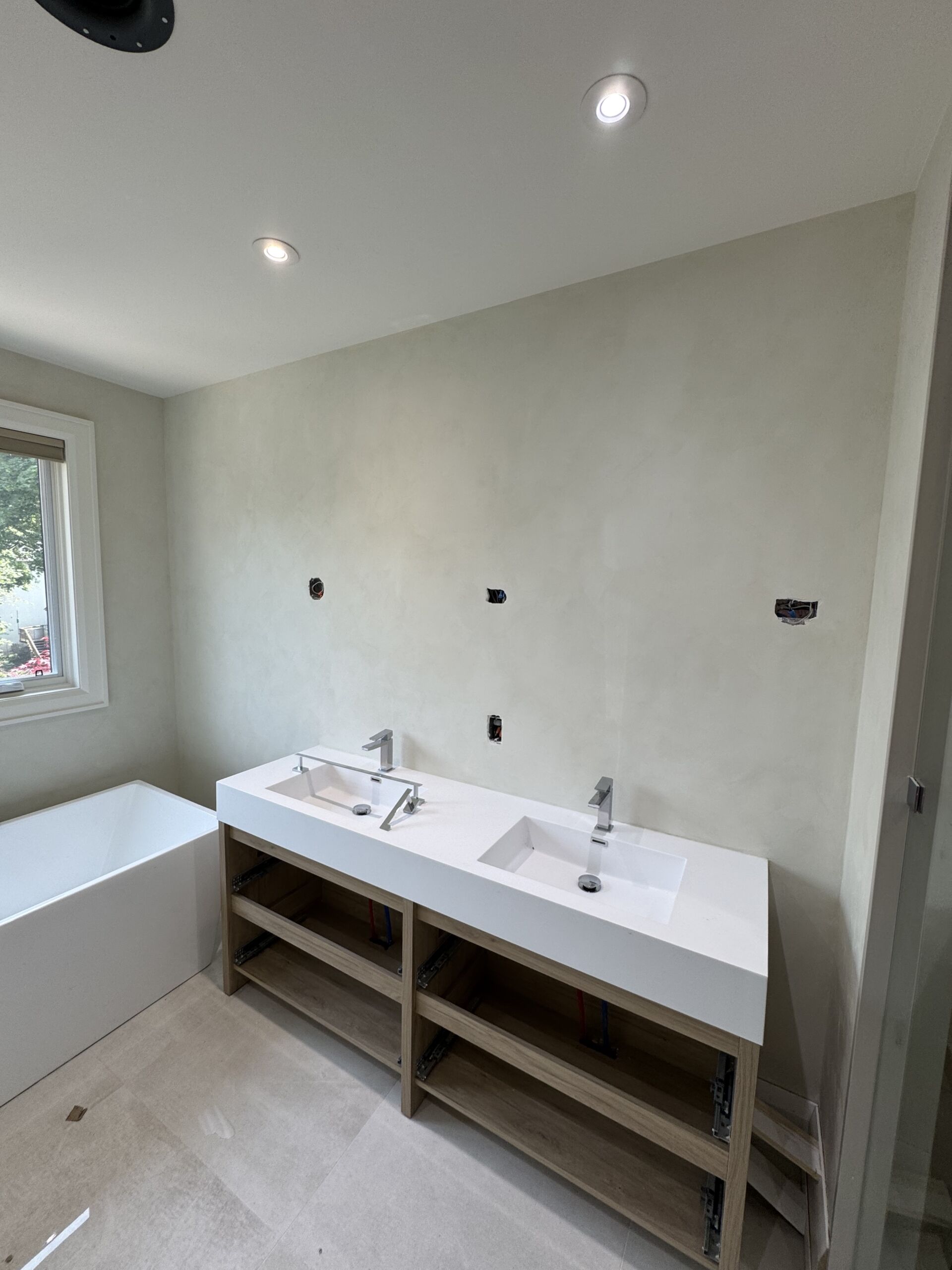 bathroom-limewash-soft-green-limewash-paint-in-toronto3 Smooth Mineral Limewash Texture: limewash bathroom walls with freestanding tub and vanity, window framing green trees outside.