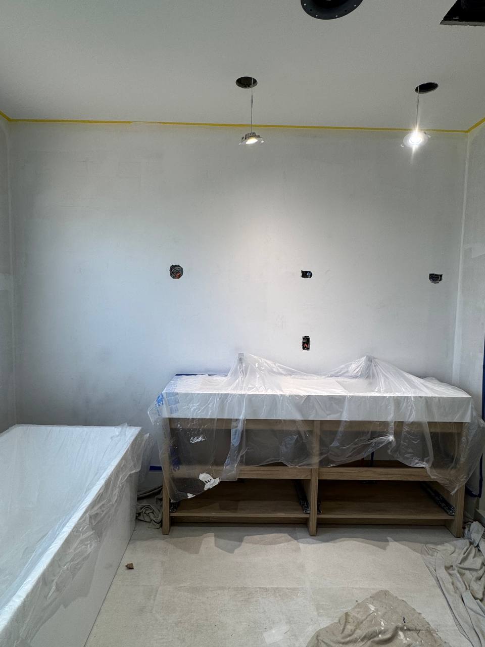 Bare bathroom walls before limewash application, with freestanding tub and window overlooking trees.