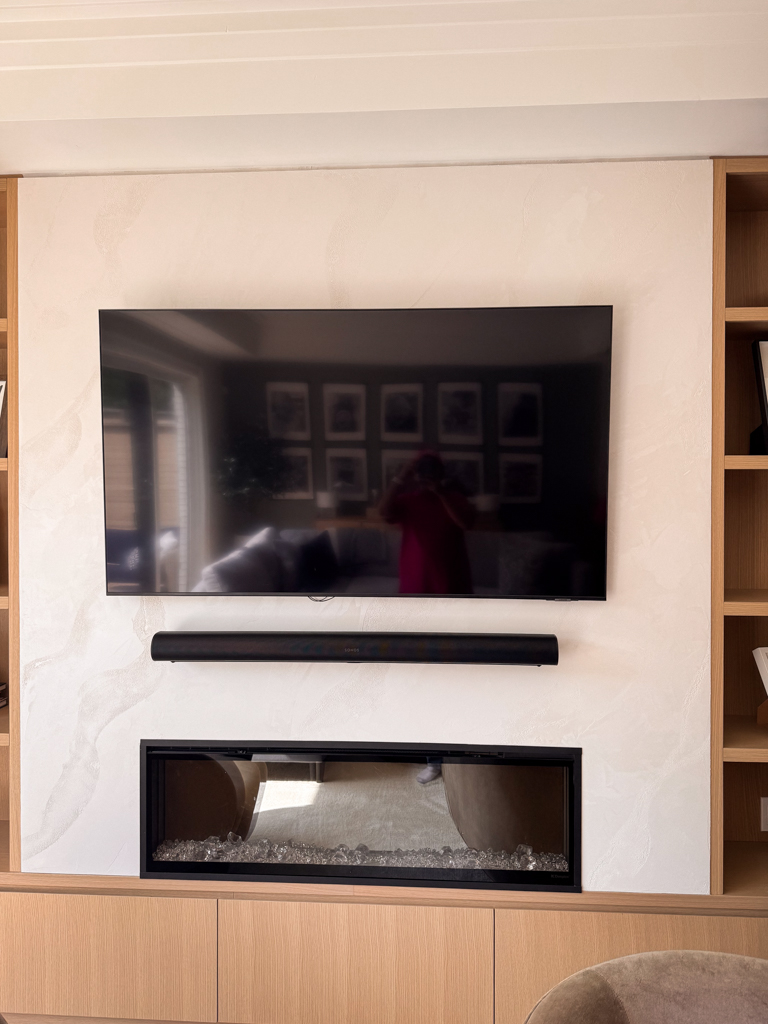 A modern living room fireplace and TV wall in Etobicoke, finished with a luminous pearly venetian plaster in a soft, light color.