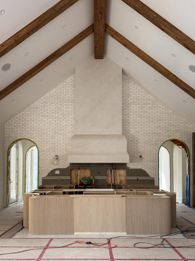 pearly-venetian-plaster-kitchen-range-hood-kleinburg Custom tall kitchen range hood finished in Pearly Venetian Plaster featuring a soft iridescent shimmer, framed by rustic wooden beams in a luxury Kleinburg farmhouse.