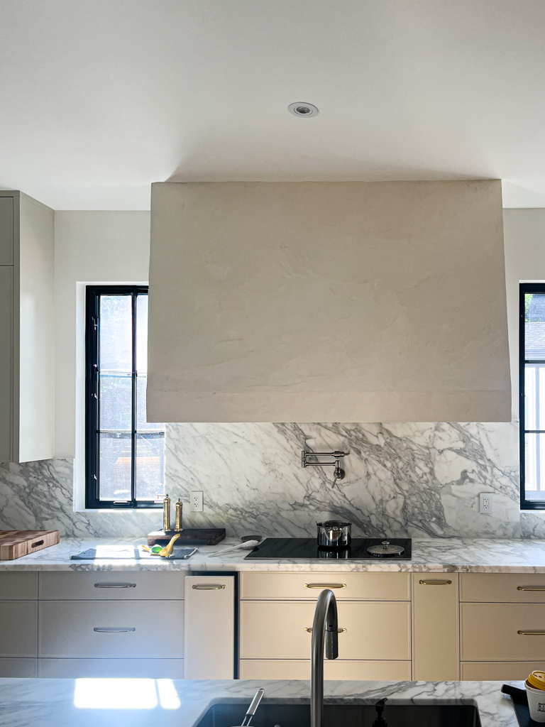 A modern white Venetian plaster range hood, seamlessly installed in a kitchen in Mississauga, Toronto.
