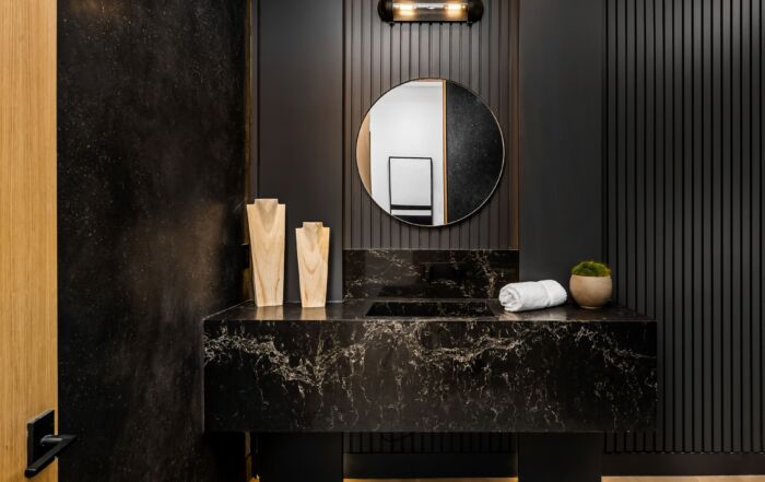 Moody powder room with dark textured Venetian plaster walls and dramatic lighting, showcasing a bold powder room design in a small space.