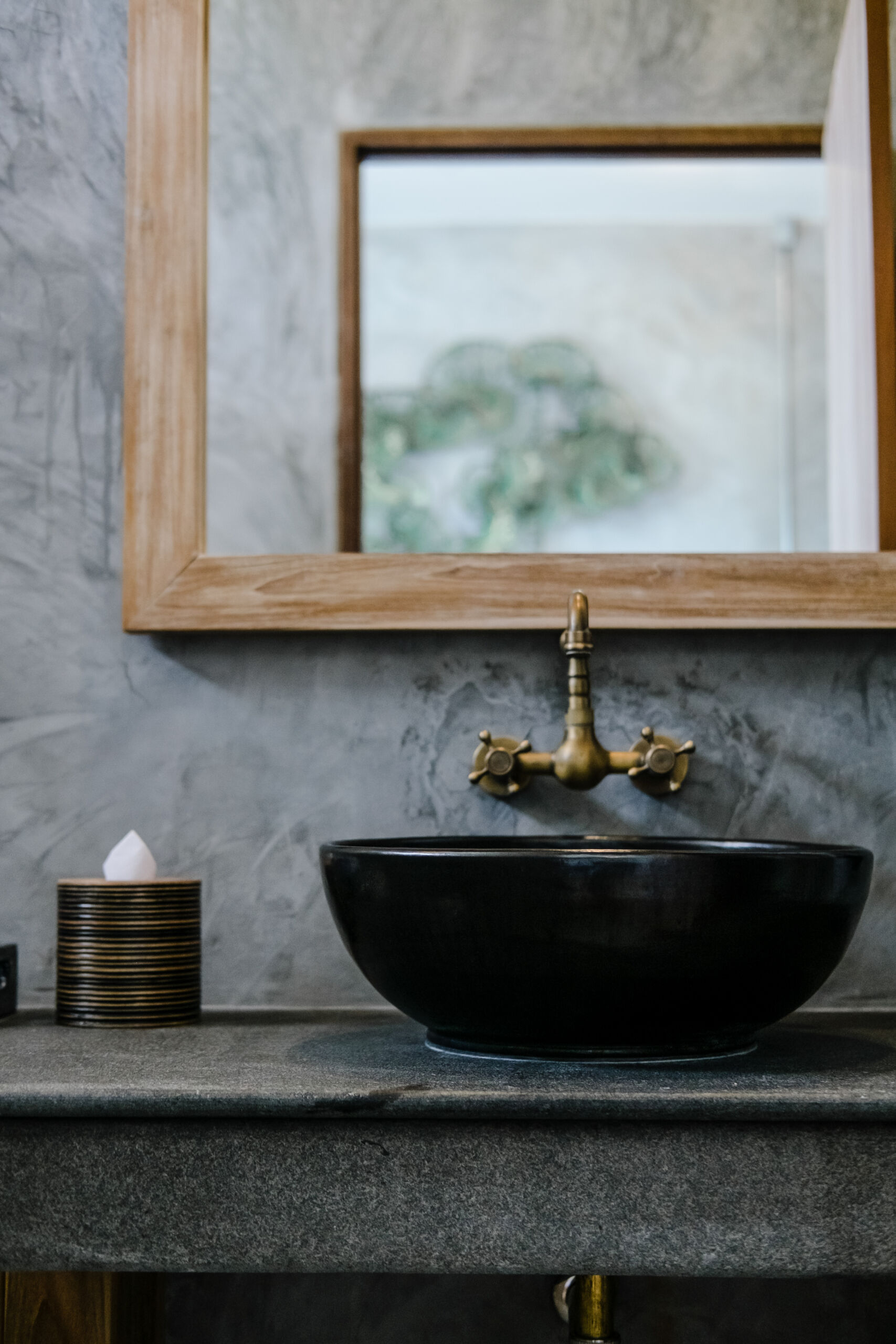 Moody bathroom design featuring a black sink with vintage copper faucet in a loft-style powder room with navy venetian plaster textured walls.