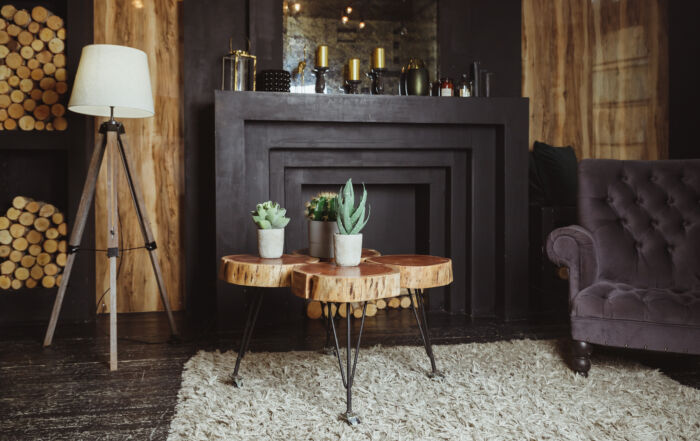 Black plastered fireplace with wooden ceiling beams in a moody, modern rustic interior