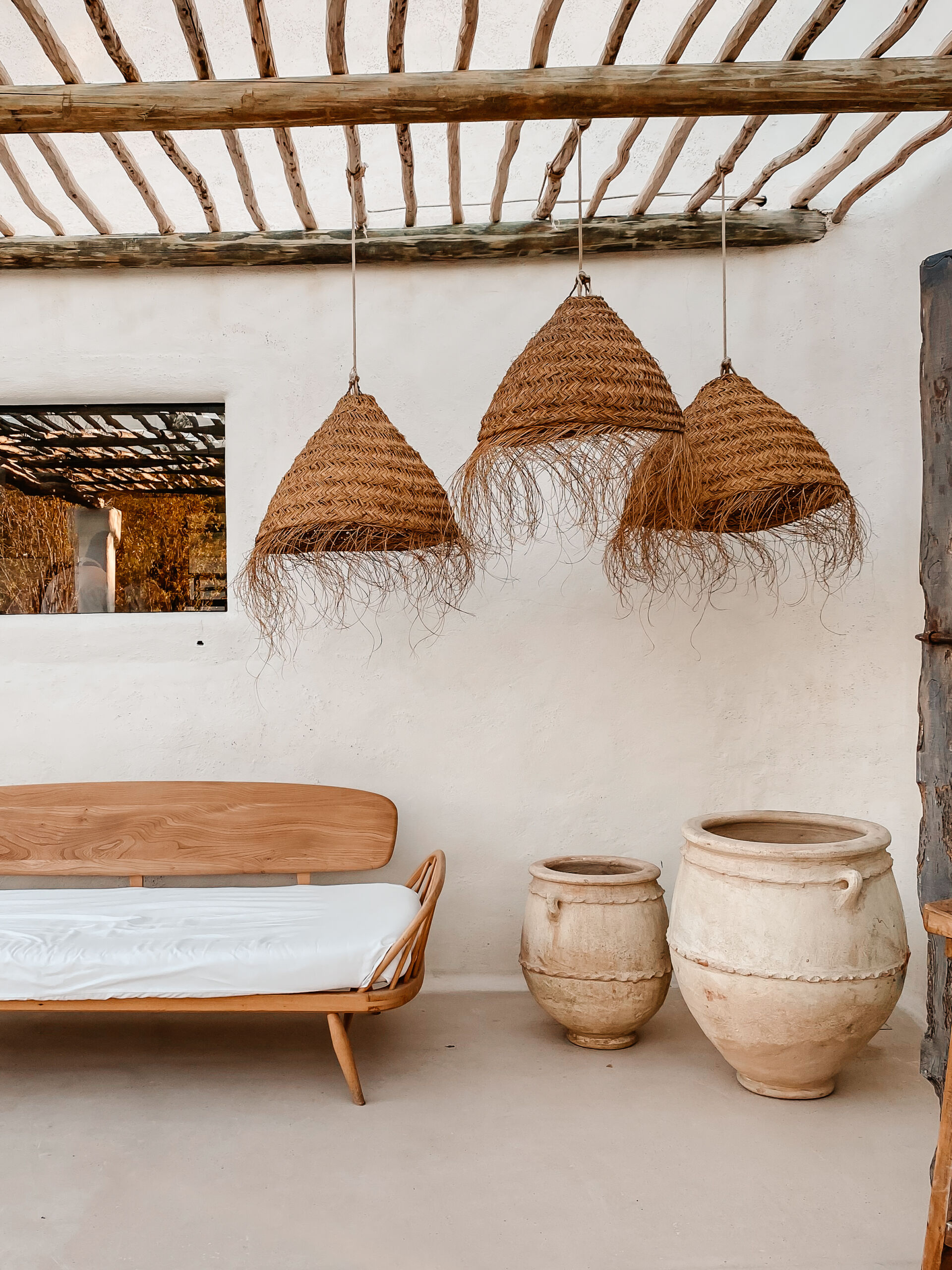 Cozy rustic exterior with soft organic look plastered walls, a bench, clay vessels and rattan lamps Exterior porch of a Florida home with plastered wall and aged rustic finish