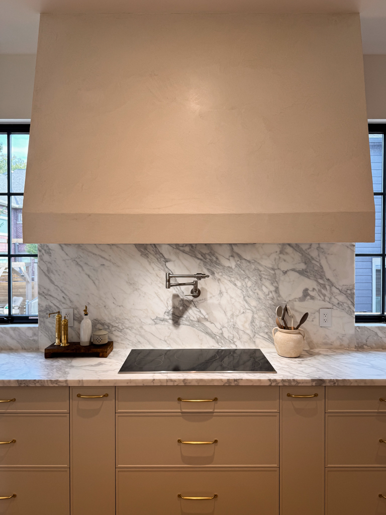 A finished kitchen hood with a smooth, off-white Marmorino Venetian plaster surface and a subtle sheen.