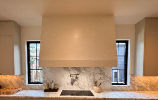 A finished kitchen hood with a smooth, off-white Marmorino Venetian plaster surface and a subtle sheen.