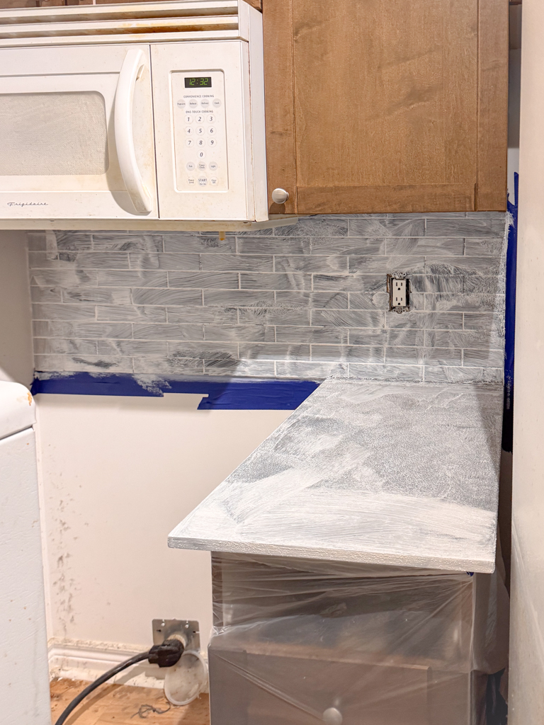 Microcement-kitchen-renovation-microcement-backsplash-microcement-countertop-yorkville,-bloor-6 A kitchen counter and backsplash primed with a bonding agent, showing a clean and prepared surface ready for the first coat of microcement.