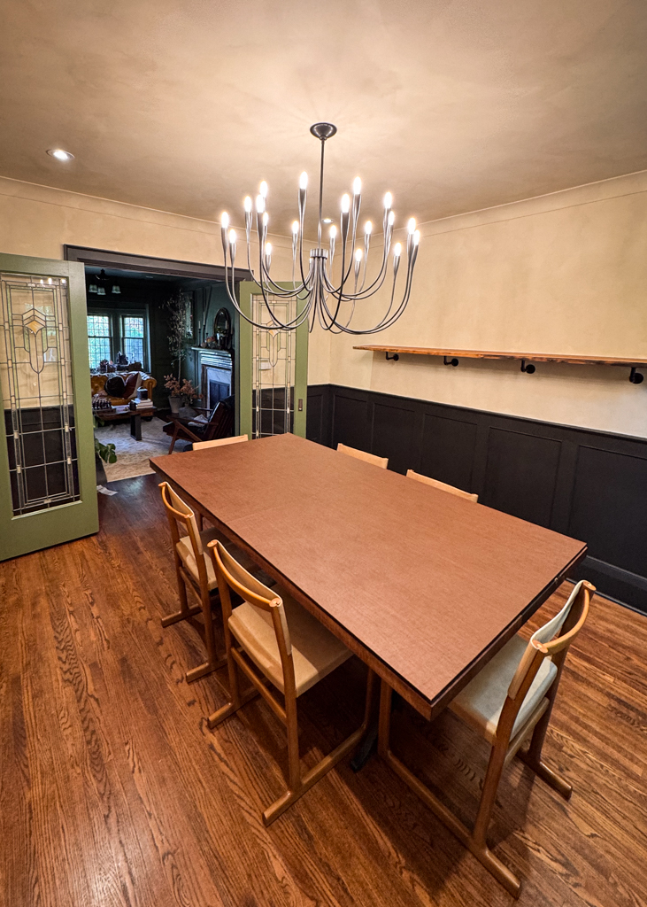 interior-limewash-dining-room-creamy-beige-bloor-west-village-toronto-2 A beautifully finished living room interior in a Tudor home, featuring creamy limewash walls and black wainscotting, creating a rich, old-world aesthetic.
