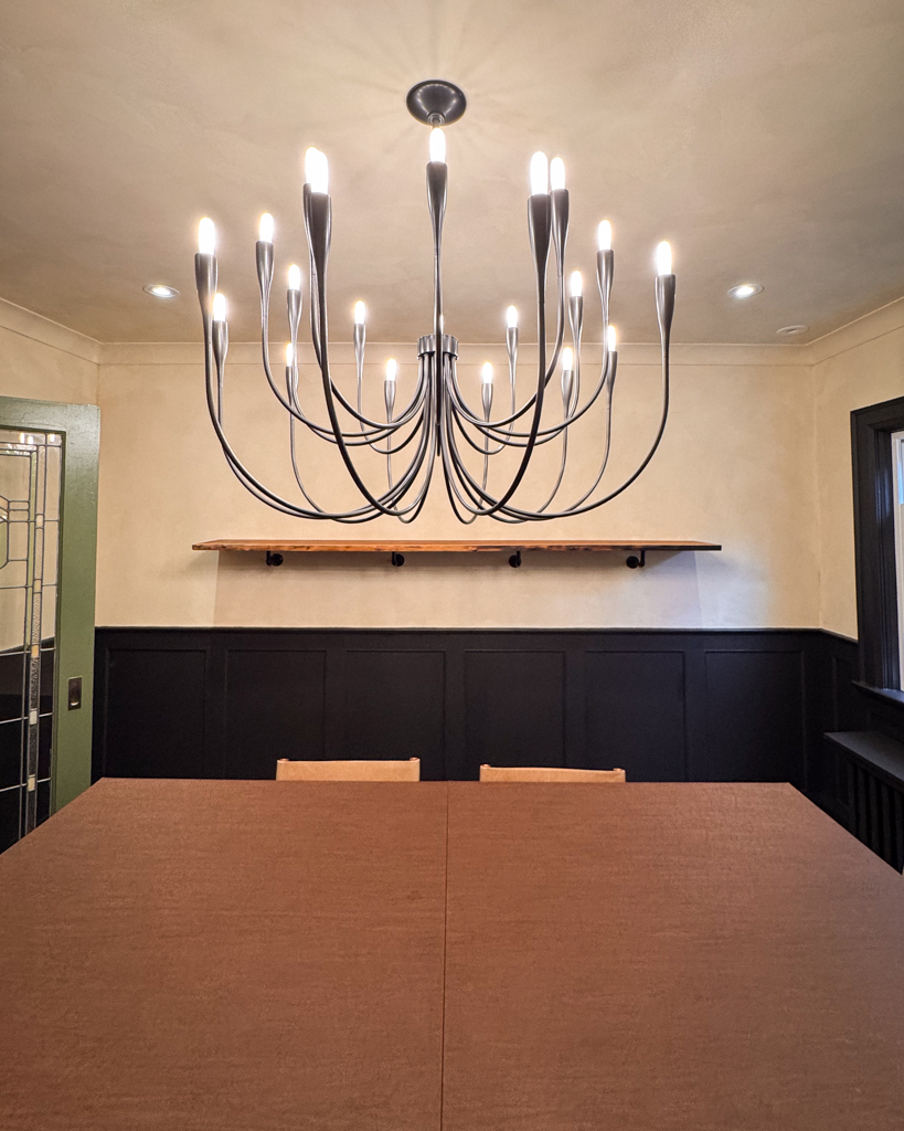 interior-limewash-dining-room-creamy-beige-bloor-west-village-toronto-5 A beautifully finished living room interior in a Tudor home, featuring creamy limewash walls and black wainscotting, creating a rich, old-world aesthetic.