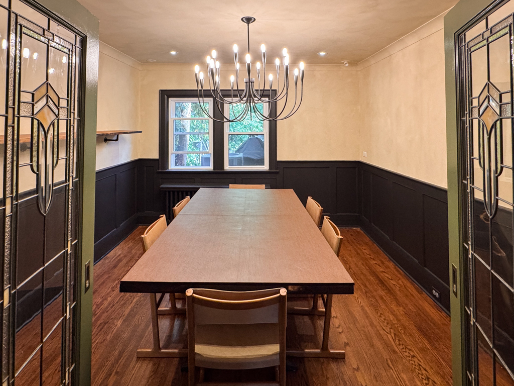interior-limewash-dining-room-creamy-beige-bloor-west-village-toronto-8 A beautifully finished living room interior in a Tudor home, featuring creamy limewash walls and black wainscotting, creating a rich, old-world aesthetic.