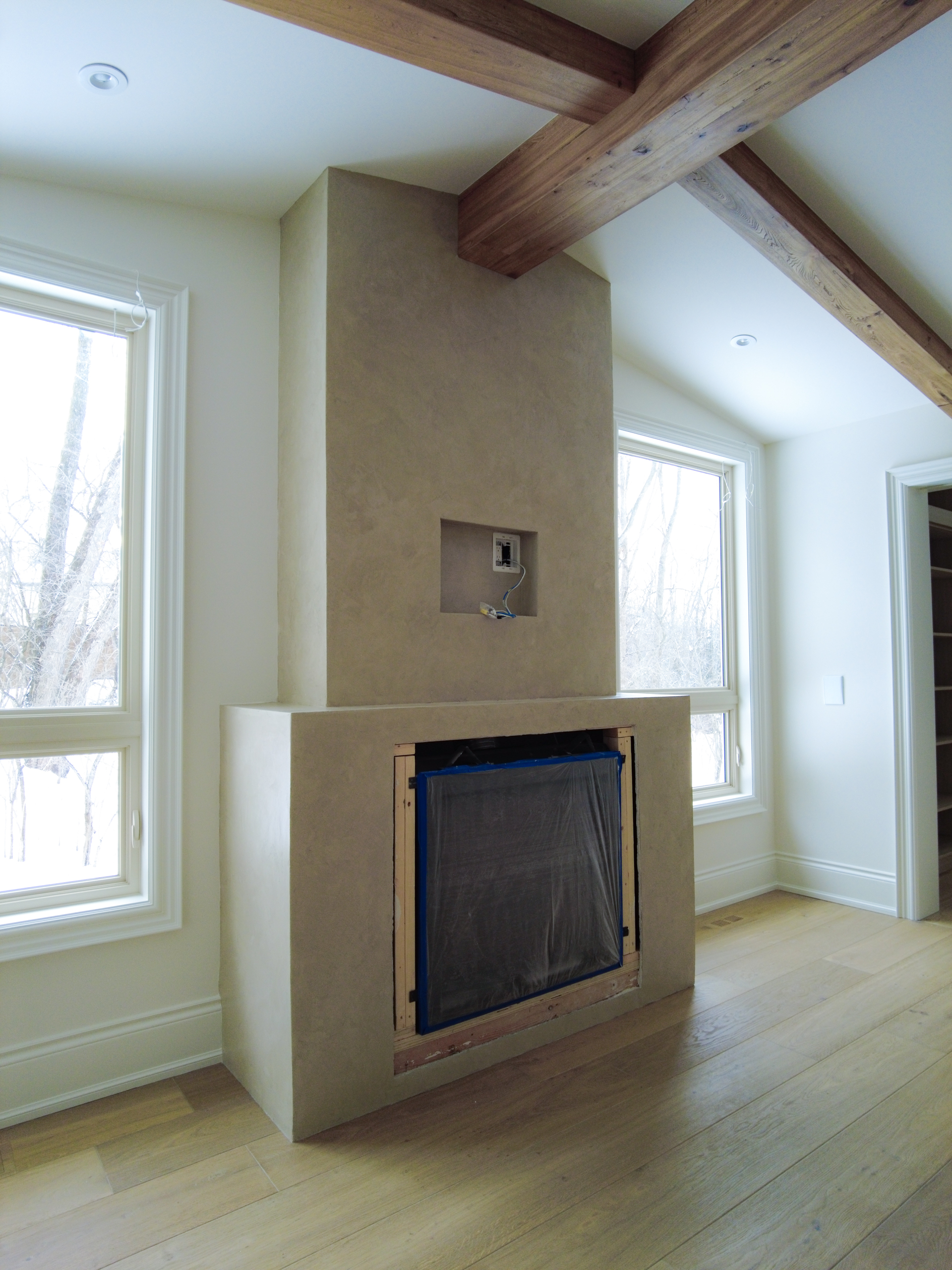 A master bedroom fireplace finished in dark beige Marmorino Venetian plaster with a flat wax coating, set within a rustic modern farmhouse interior in Kleinburg, Toronto.