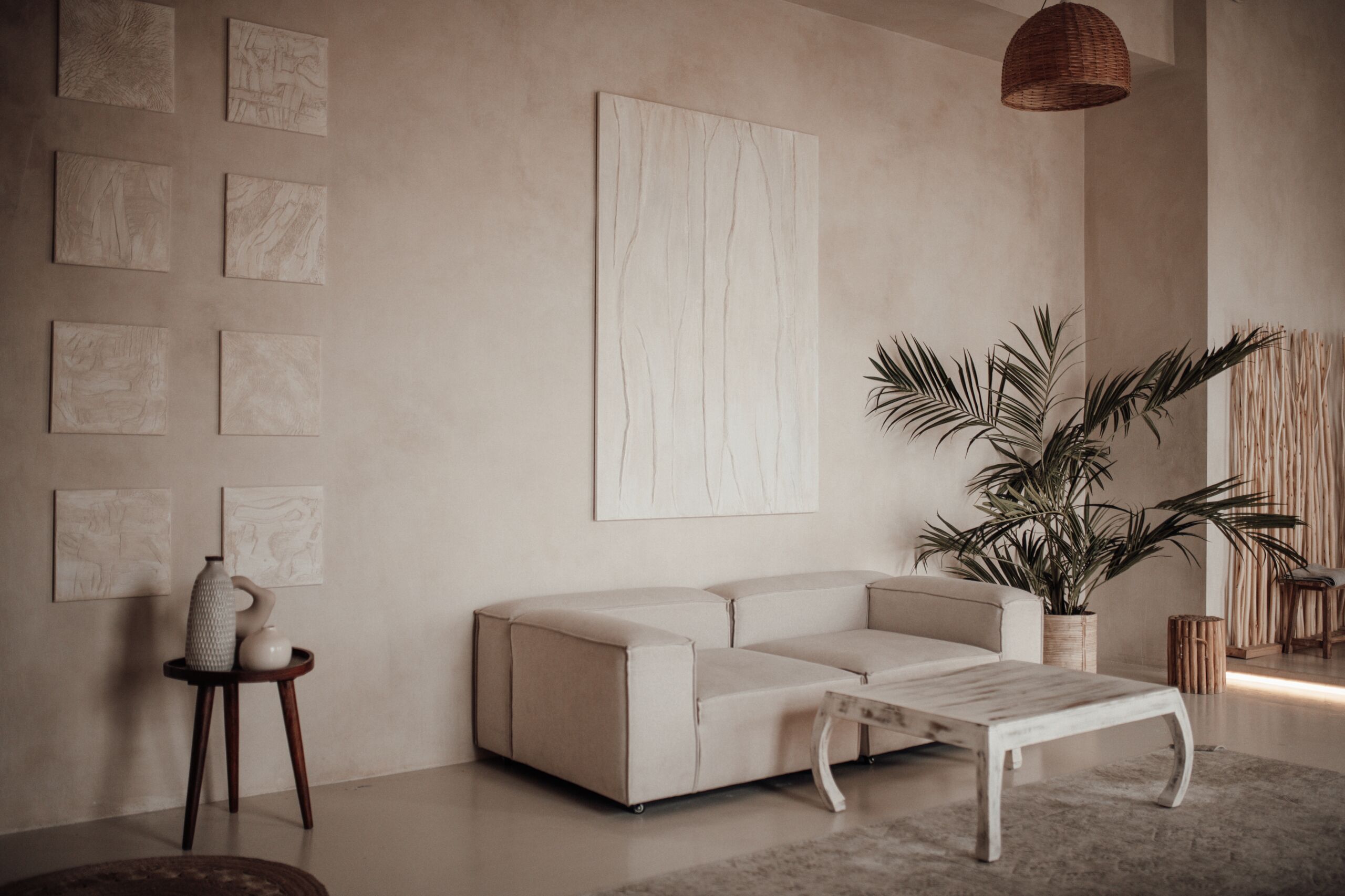 Seamless Linen Microcement Walls & Floors in Eclectic Minimalist Interior Bright open-space living room with linen-colored microcement walls and floor, featuring wood accents, tropical plants, and an eclectic mix of Indonesia-inspired textiles.