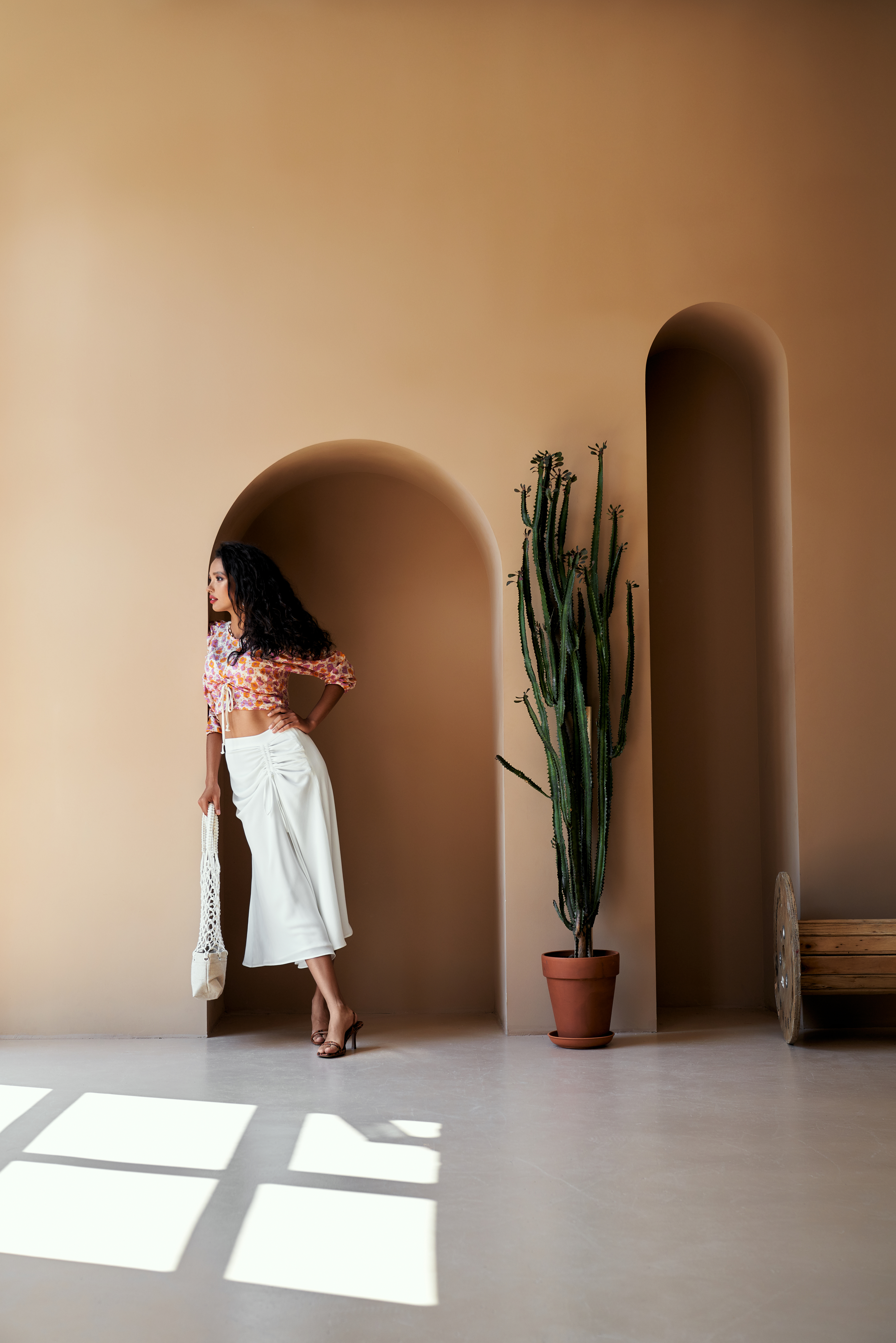 tuscan-style-walls-sand-limewash-interior Girl standing next to Tuscan-style walls with a seamless sand-colour limewash finish, reflecting a natural stone interior design palette.