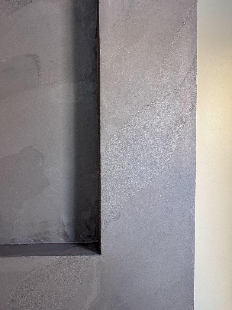 Close-up of dried plum Venetian plaster with pearlescent shimmer and intricate hand-troweled veining.