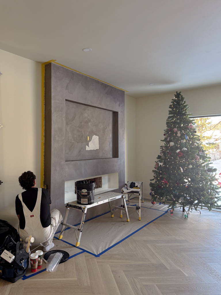 Floor-to-ceiling fireplace finished in moody plum pearlescent Venetian plaster in a modern living room.