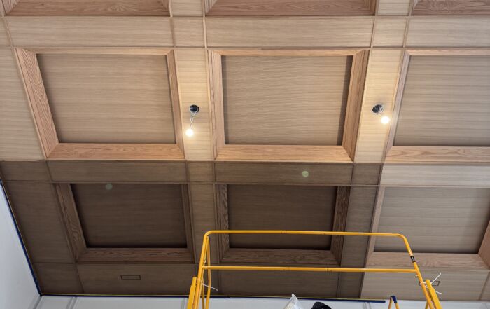 Luxury coffered ceiling featuring custom-stained red oak ceiling panels and crisp white framing, protected by a professional varnish and accented with integrated hidden lighting.