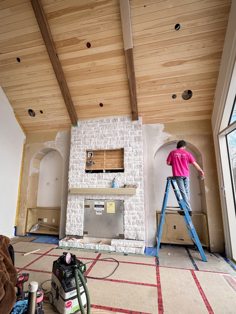 Seamless-Microcement-built-in-media-wall-kleinburg A raw, unfinished built-in media wall constructed of MDF and plywood, meeting a floor-to-ceiling stone fireplace in a Kleinburg custom home before being finished in microcement.