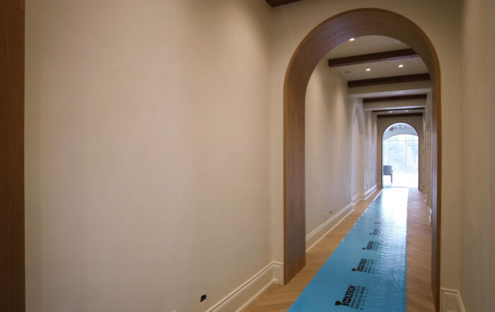 A finished luxury hallway at Kleins Ridge with soft warm white Venetian Plaster walls and ceiling, perfectly integrated with dark walnut beams.