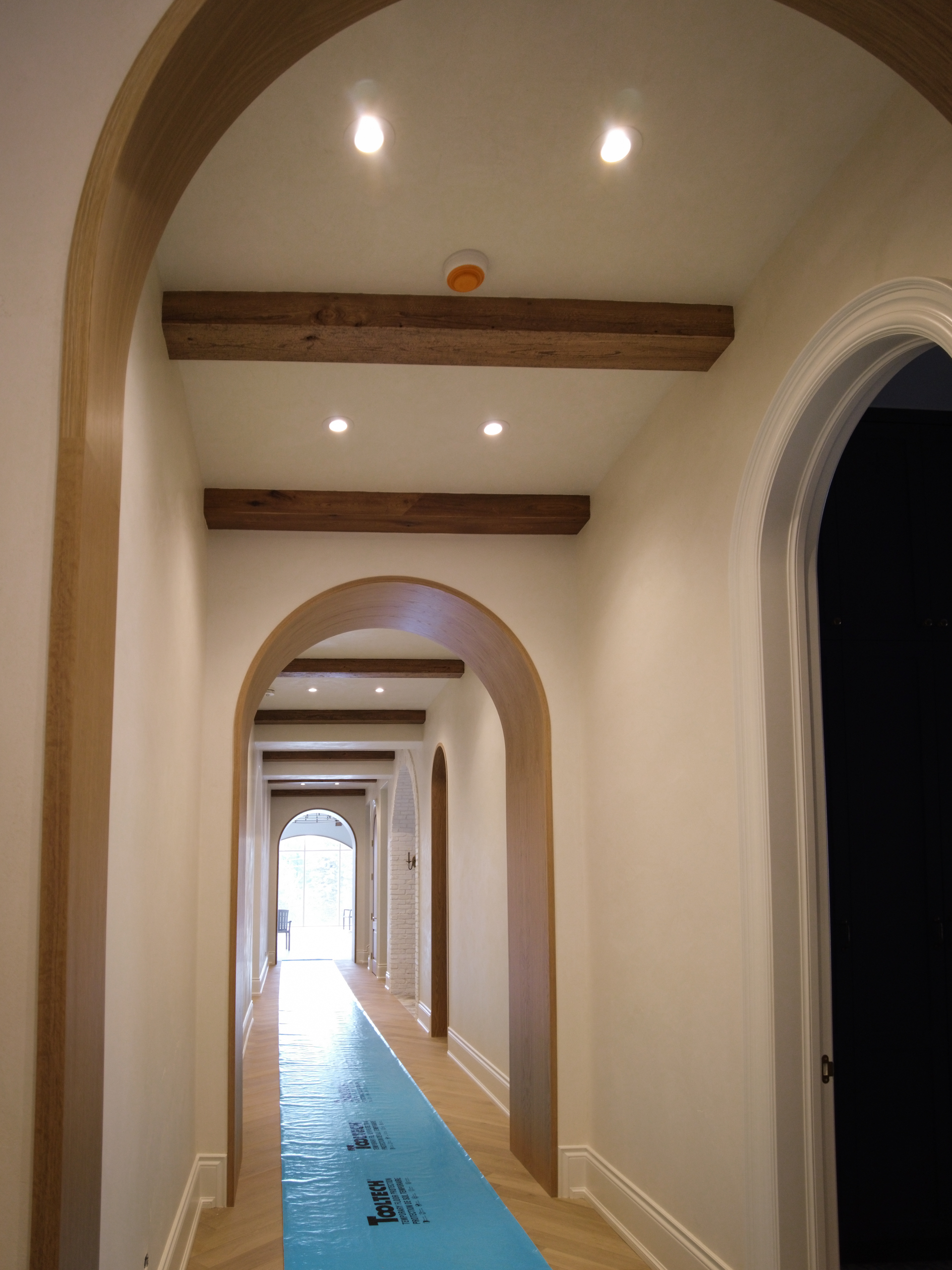 A finished luxury hallway at Kleins Ridge with soft warm white Venetian Plaster walls and ceiling, perfectly integrated with dark walnut beams.