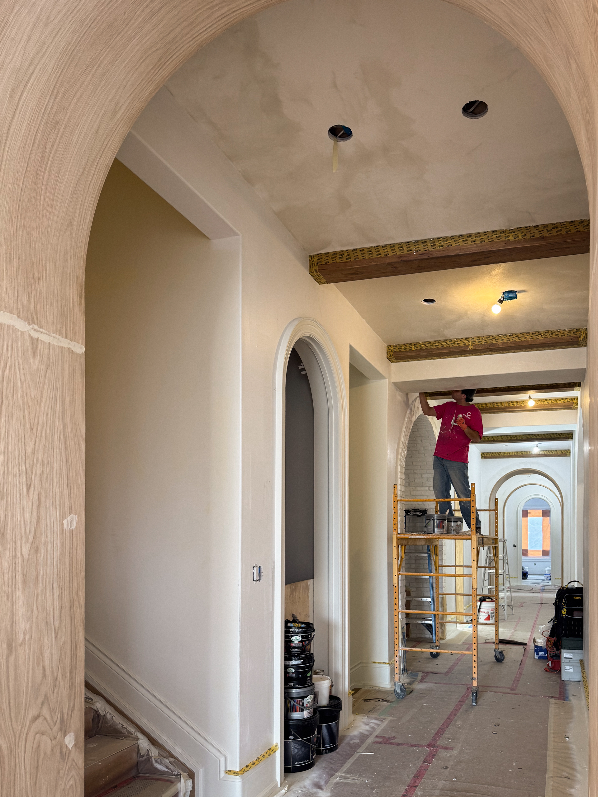 Close-up of an artisan hand-applying a warm white Marmorino Venetian Plaster over drywall, utilizing a skip-trowel technique to mimic natural limestone.