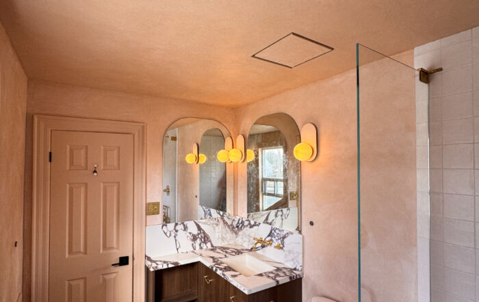 A small, modern bathroom featuring seamless matte Venetian Plaster walls in a warm pinkish-beige tone, creating a soft, cloudy texture that wraps around a minimalist vanity.