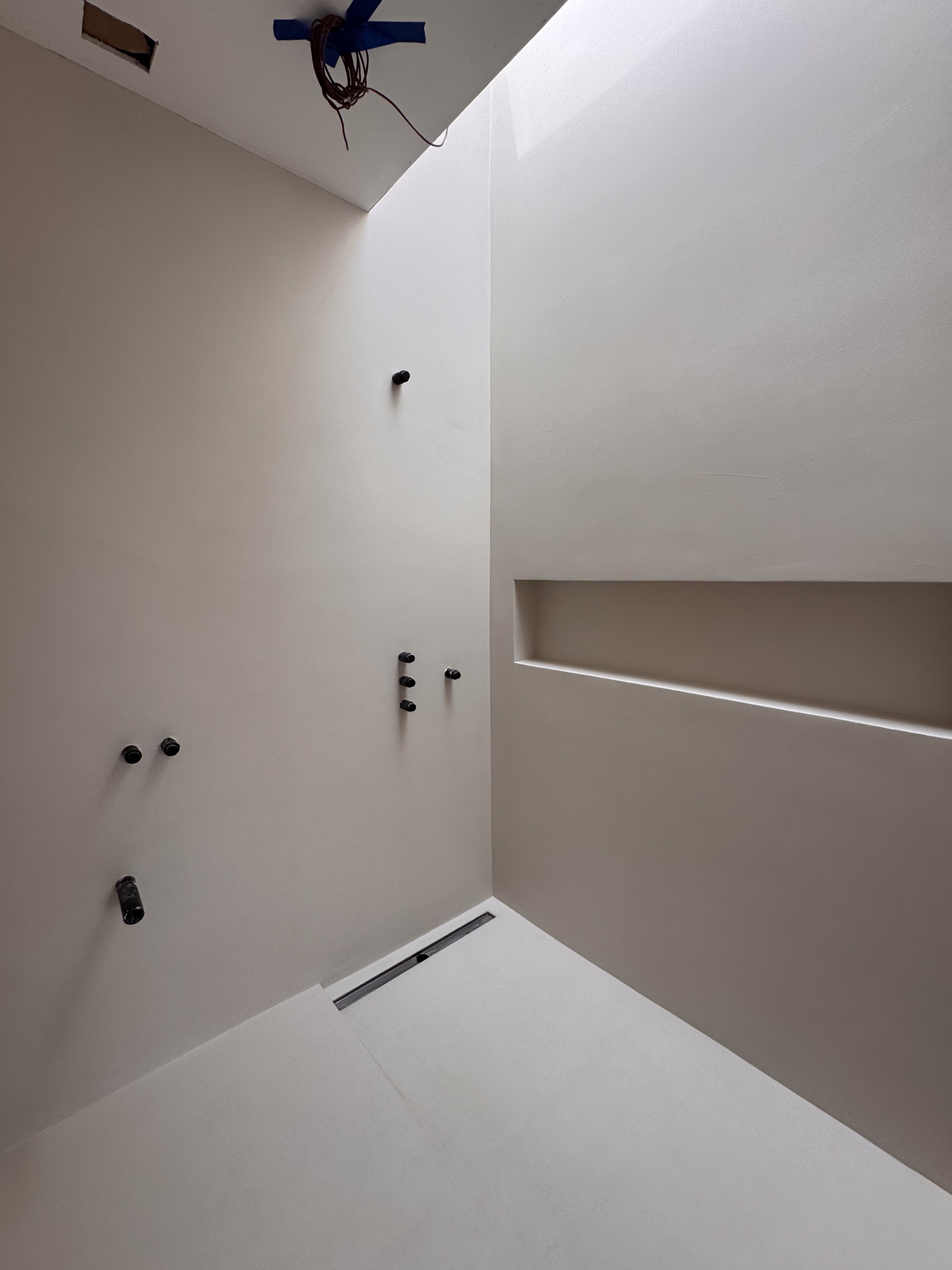 microcement-bathroom-walls-floor-richmondhill-toronto A modern bathroom in Richmond Hill featuring seamless microcement walls and floors in a warm soft grey, with a floating vanity and minimalist black fixtures.