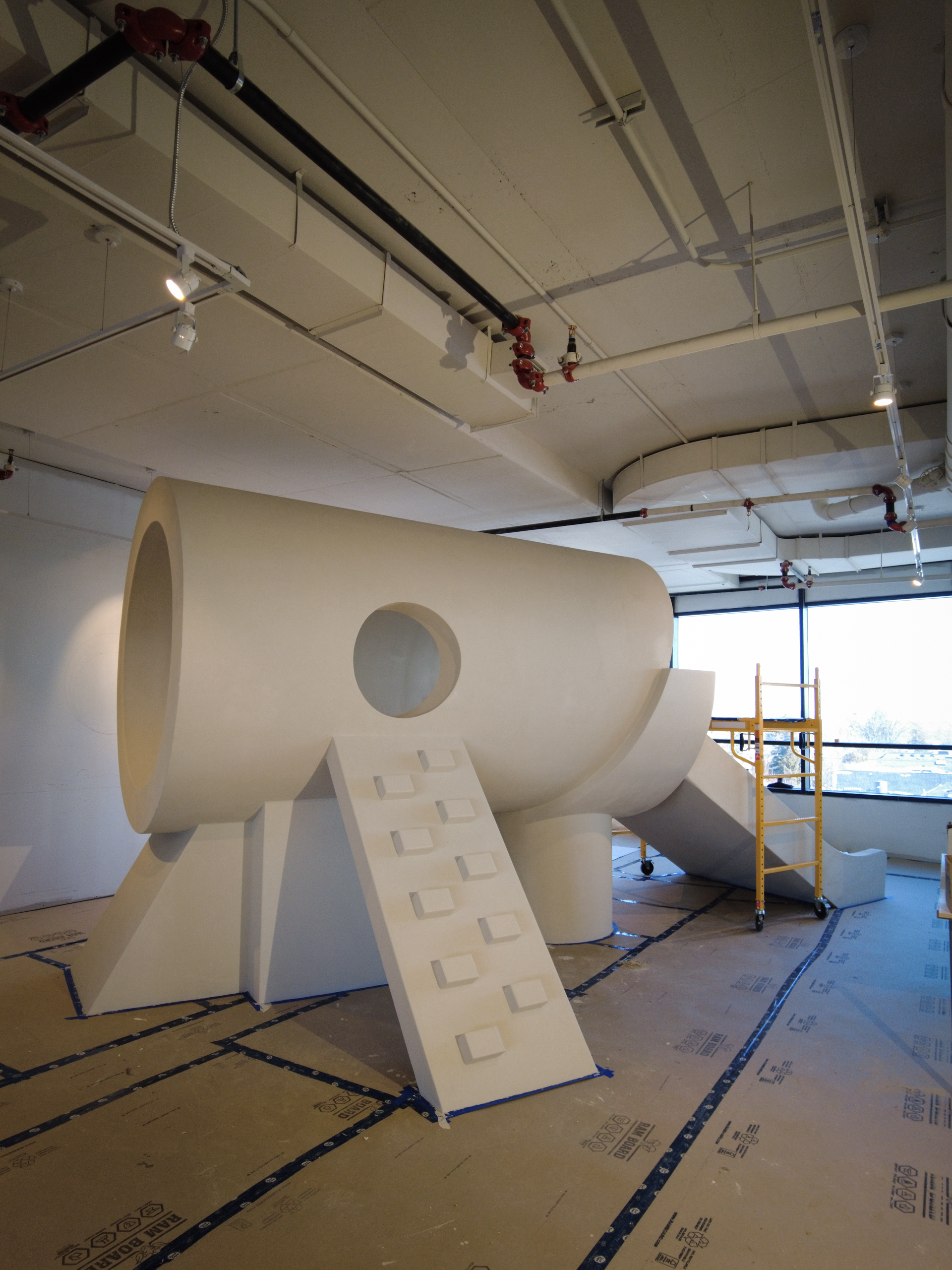 Large-scale indoor playground structures, including climbing blocks and slide surrounds, finished in a continuous, hand-applied microcement.
