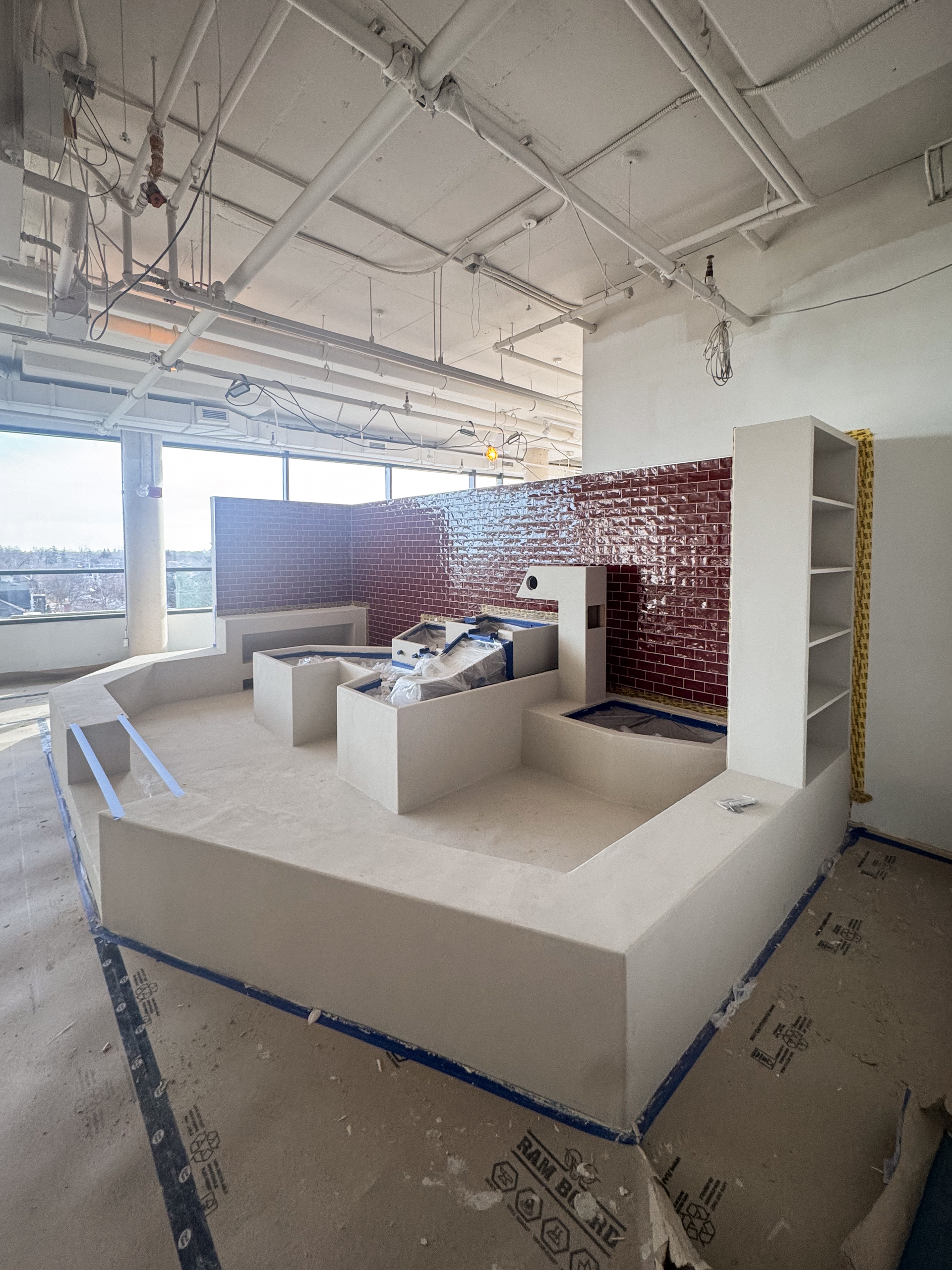 Large-scale indoor playground structures, including climbing blocks and slide surrounds, finished in a continuous, hand-applied microcement.