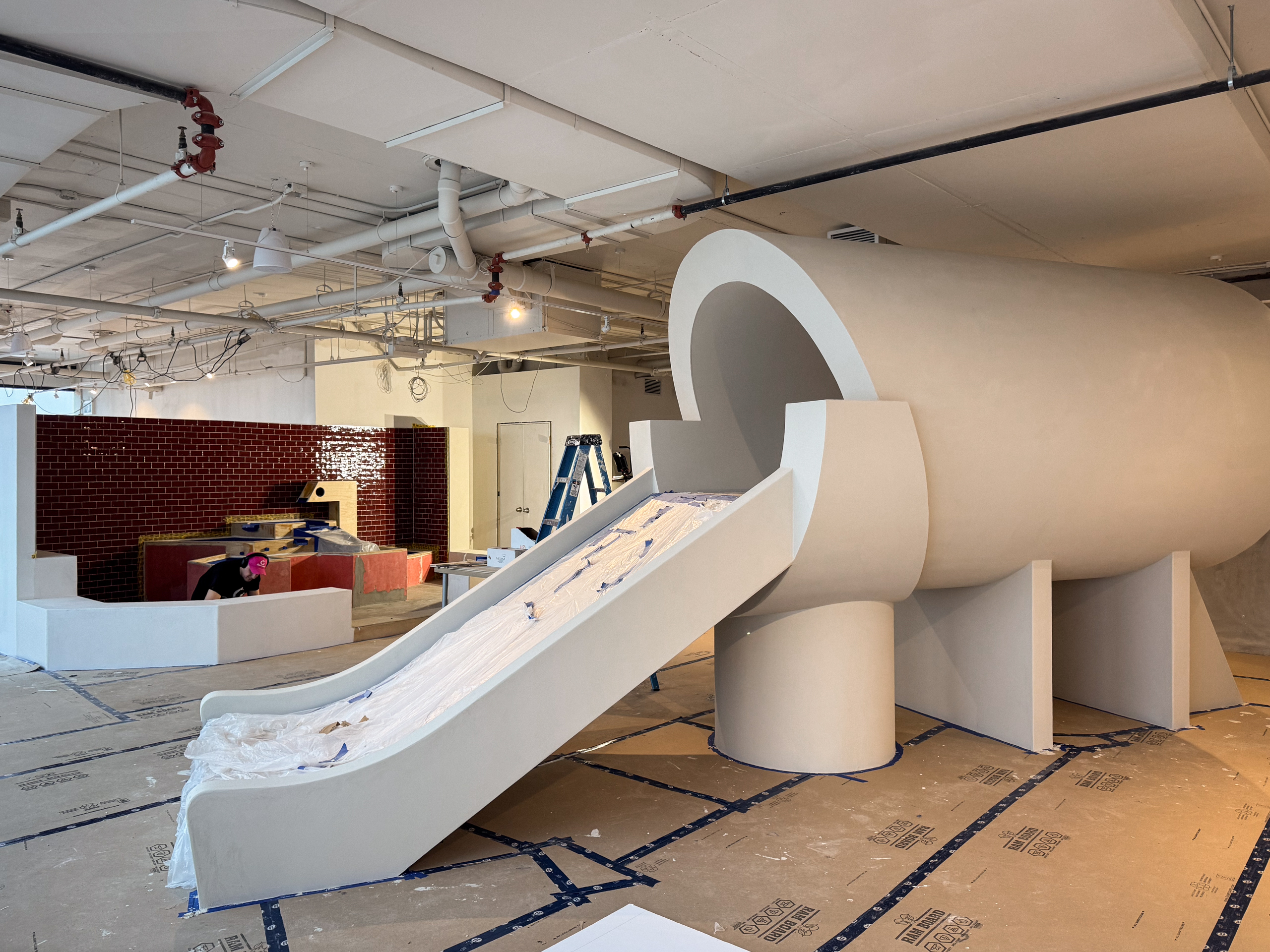 Large-scale indoor playground structures, including climbing blocks and slide surrounds, finished in a continuous, hand-applied microcement.