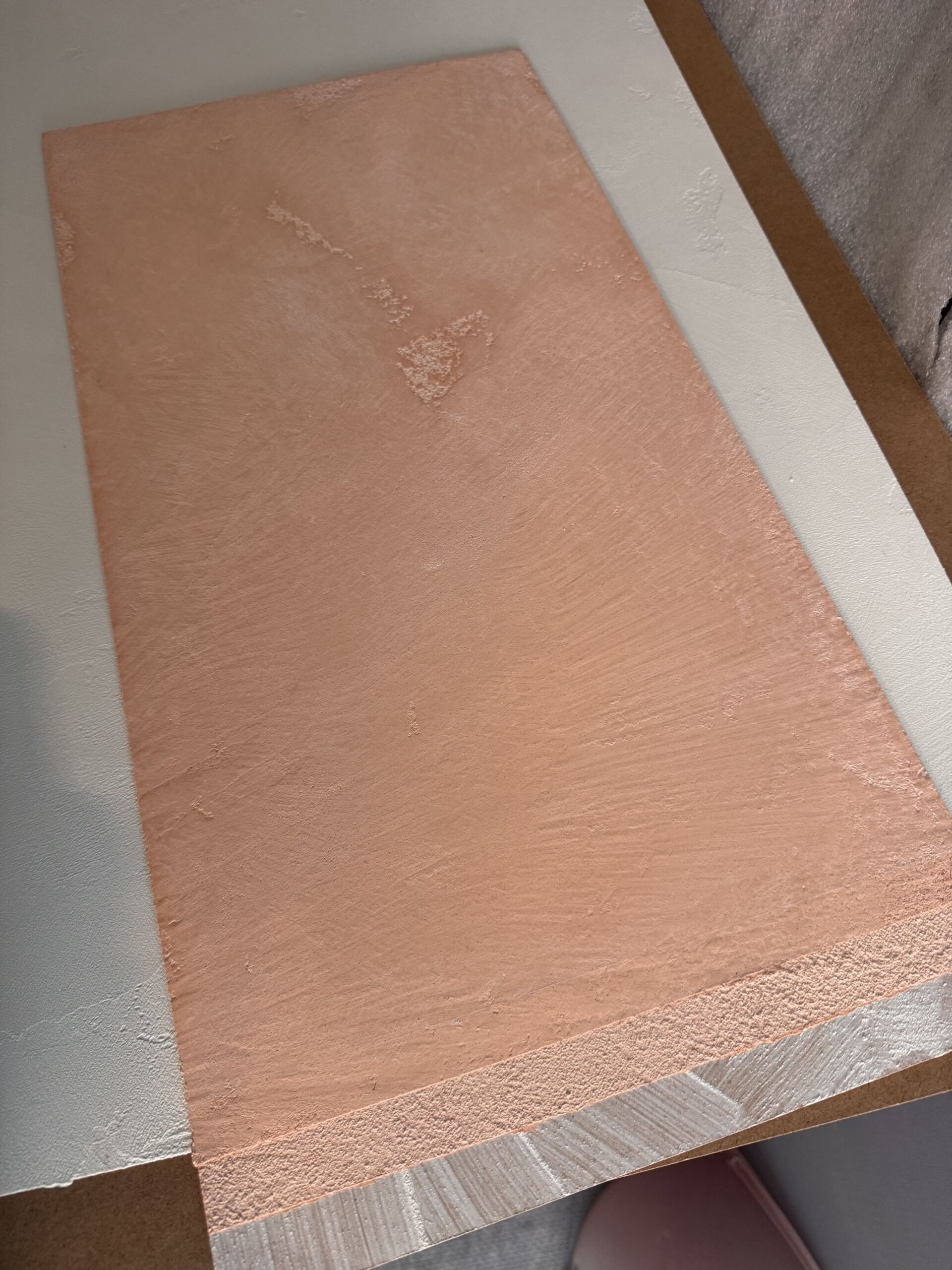 A close-up view of a custom Venetian plaster sample board in a soft dusty pink (Benjamin Moore Conche Shell), showcasing the hand-troweled texture and a perfectly matte, breathable finish.