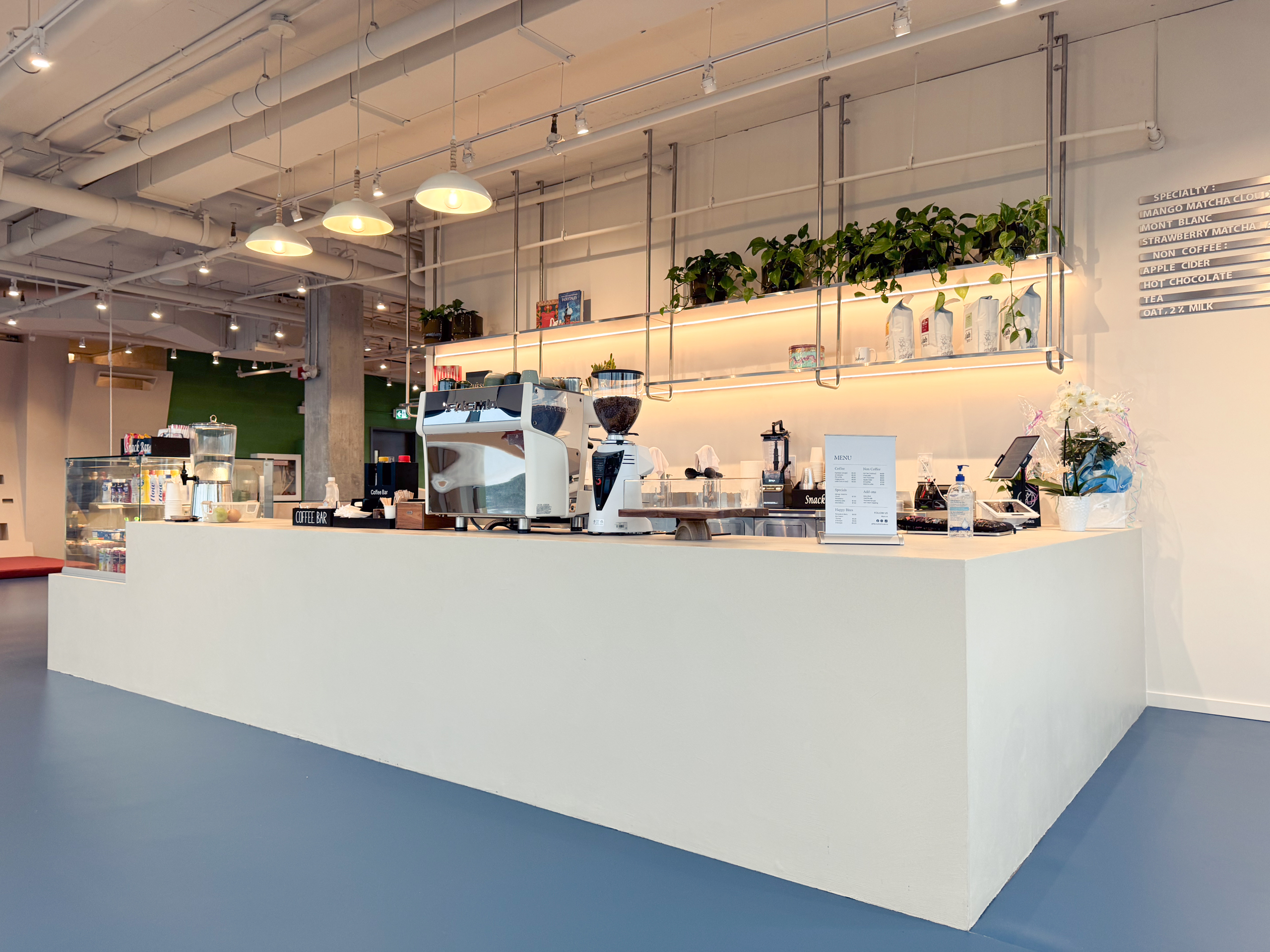 A modern indoor playground café in Toronto featuring a monolithic microcement service counter and matching built-in bench seating in a soft, matte greige finish.