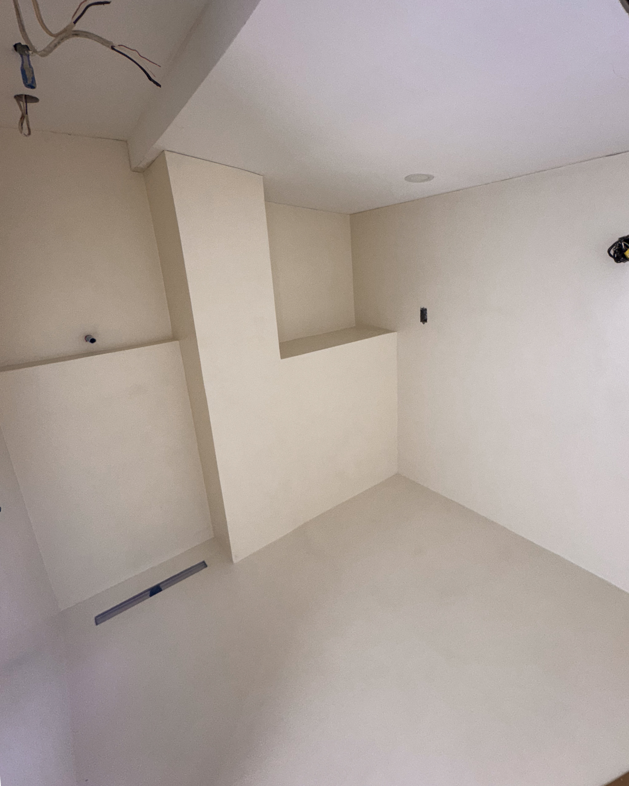 Grout-free modern walk-in shower wrapped in off-white microcement walls and floors with minimalist brass fixtures in a Leslieville home.