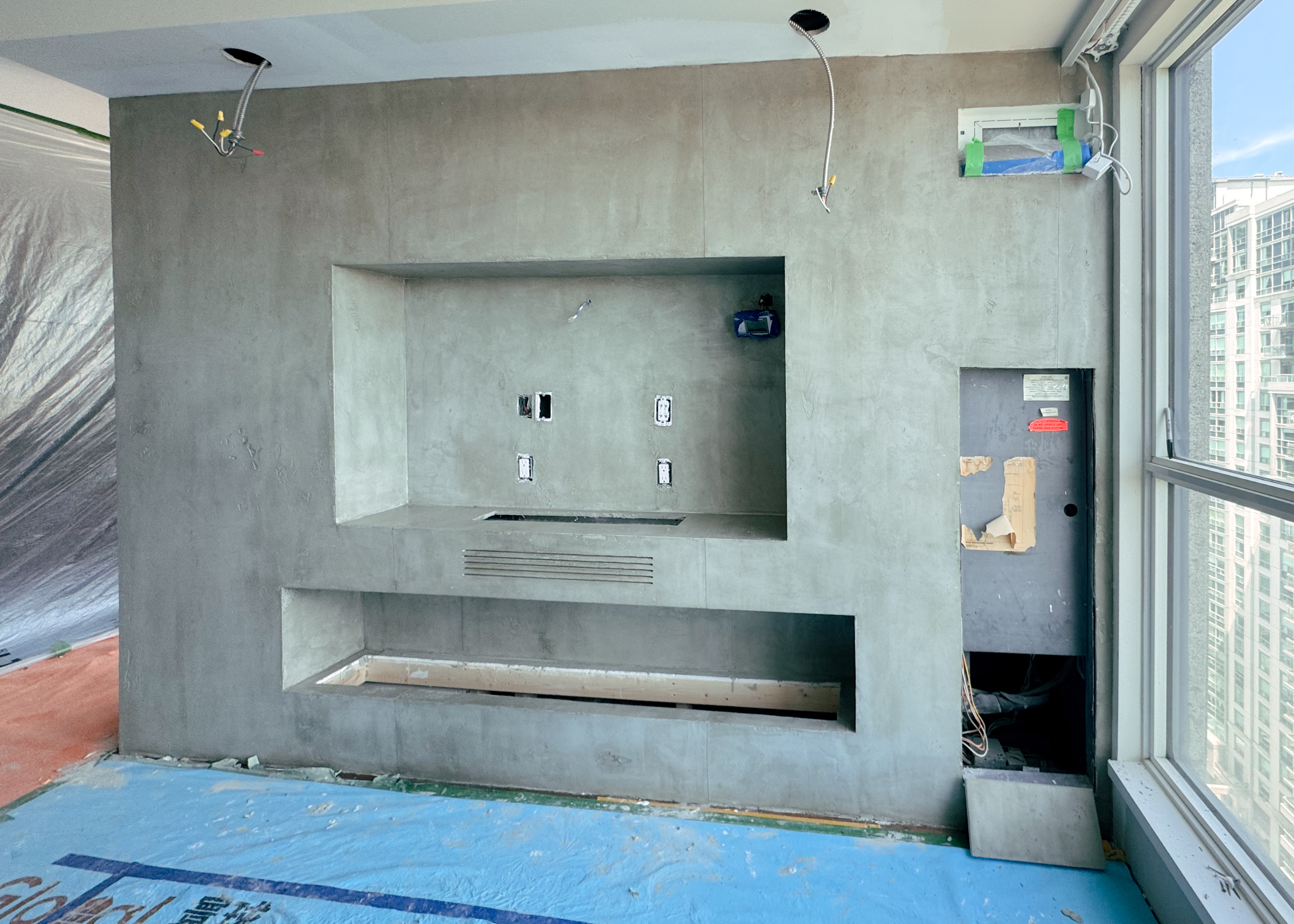 Master artisan hand-troweling a concrete effect microcement onto a double-sided fireplace in a North York home.