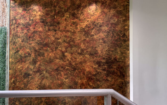 A dramatic grand stairway accent wall featuring black, red, and gold venetian plaster walls in a luxury Toronto home by Shane Baghai Development.